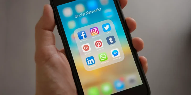 person holding mobile phone display shows social apps